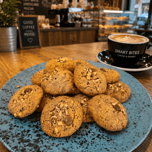 Biscuiți cu ciocolată și alune lângă cafea.
